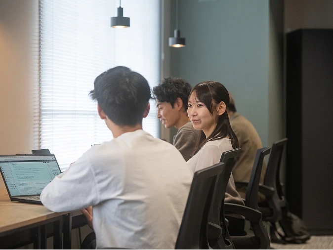 社員がオフィスでパソコンを使いながら打ち合わせをしている様子